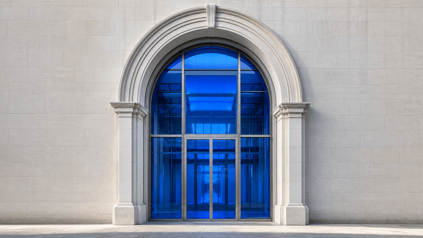 A stone archway with a modern glass-and-steel door glowing cobalt blue from within