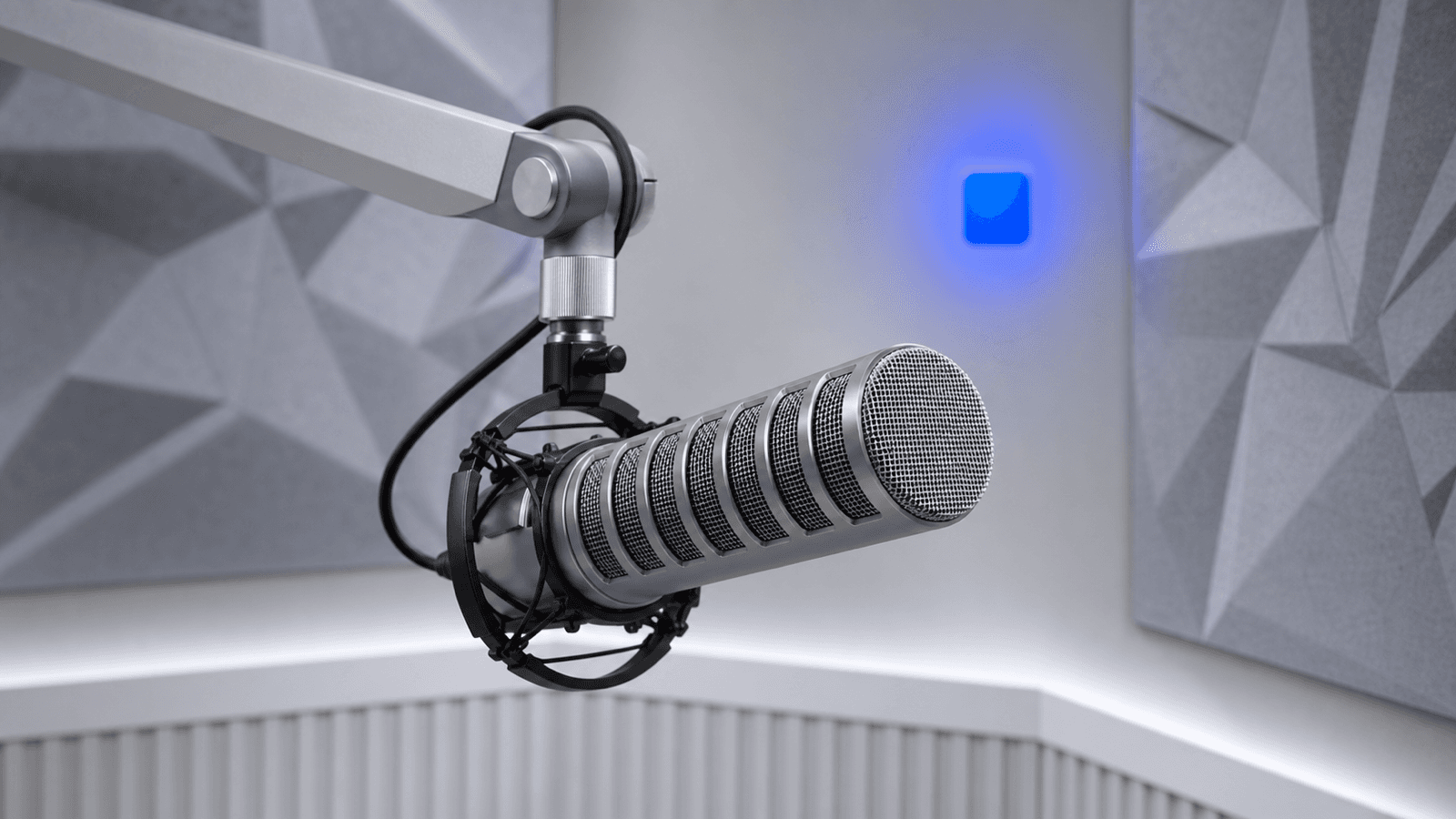 A professional broadcast microphone on an articulated arm in an acoustically treated podcast studio with grey diffuser panels and a glowing blue accent light