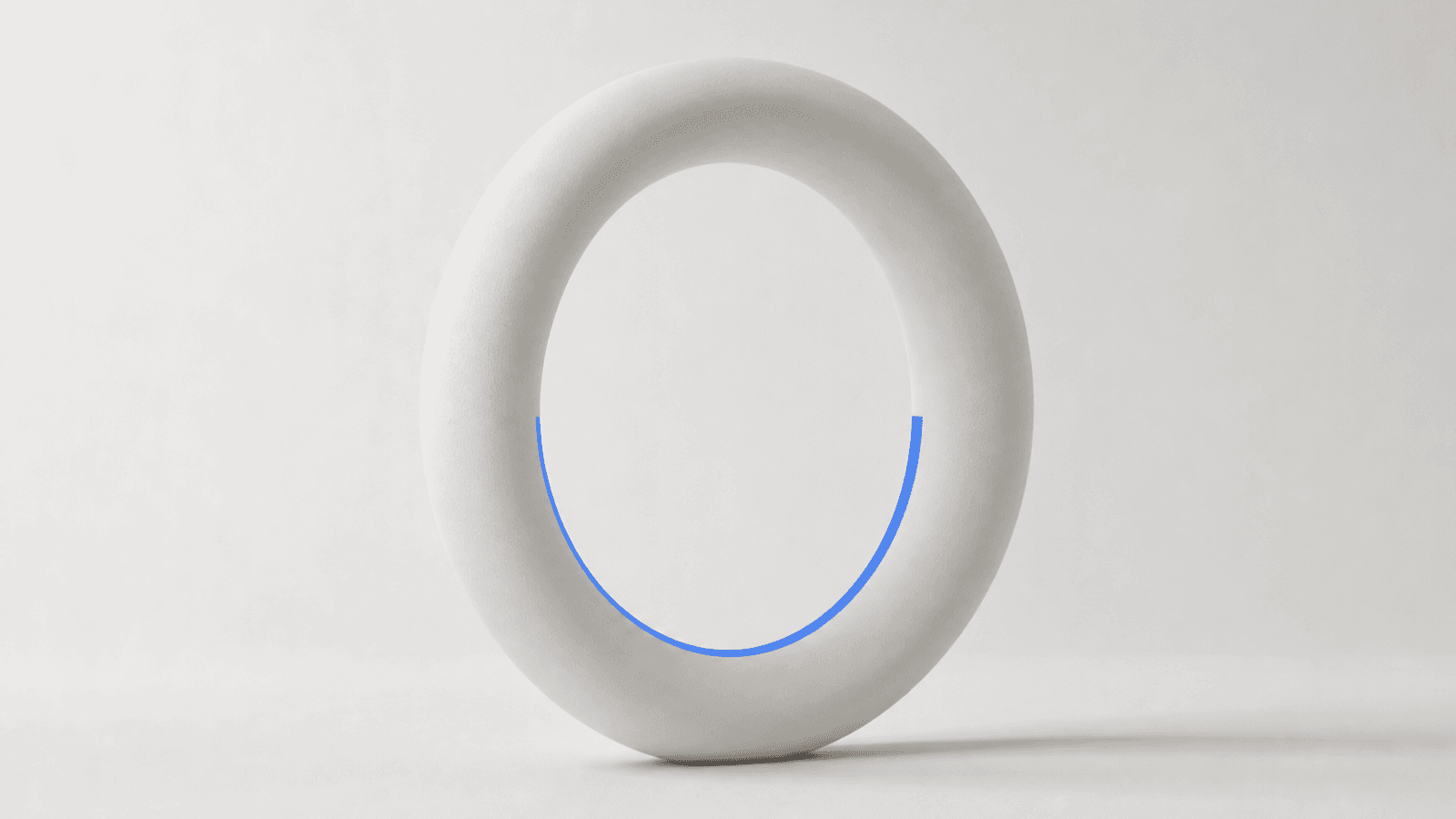 A large white ceramic ring standing on its edge, with a thin cobalt light tracing halfway around its inner rim