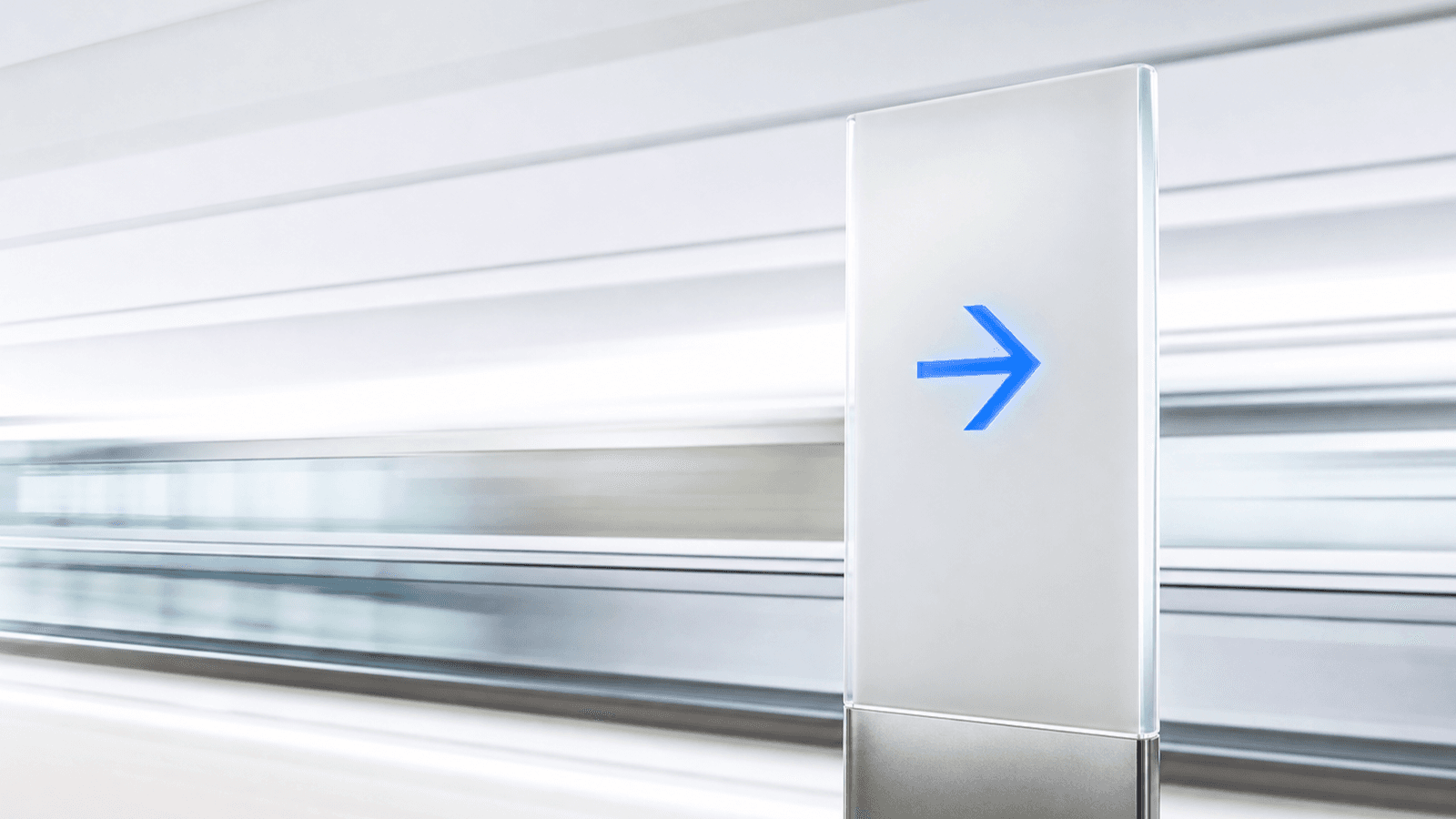 A frosted directional wayfinding signage post with a cobalt-lit arrow, set against a softly blurred motion-streak background