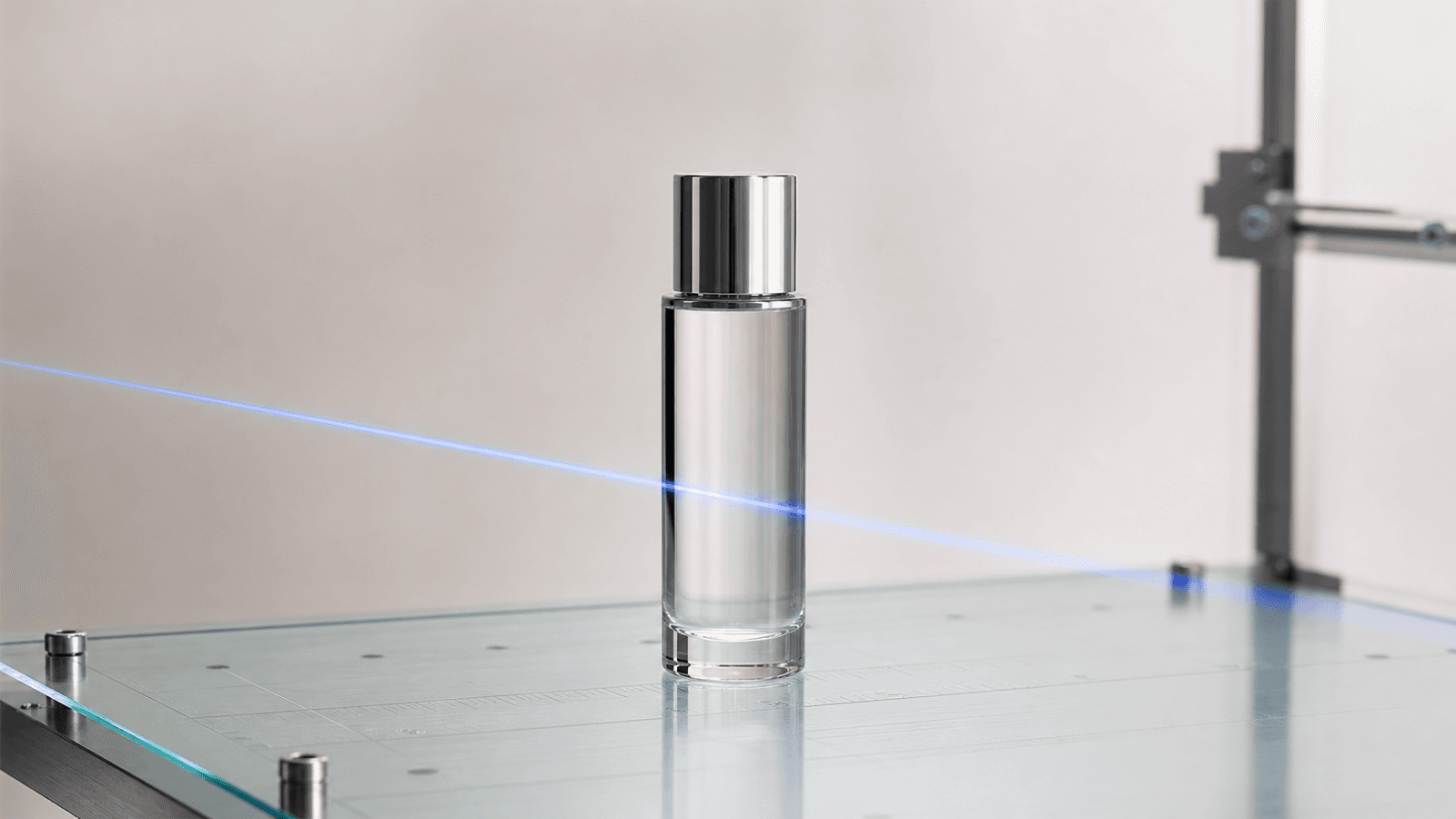 A single skincare bottle on a glass optical measurement table crossed by a cobalt scan-beam